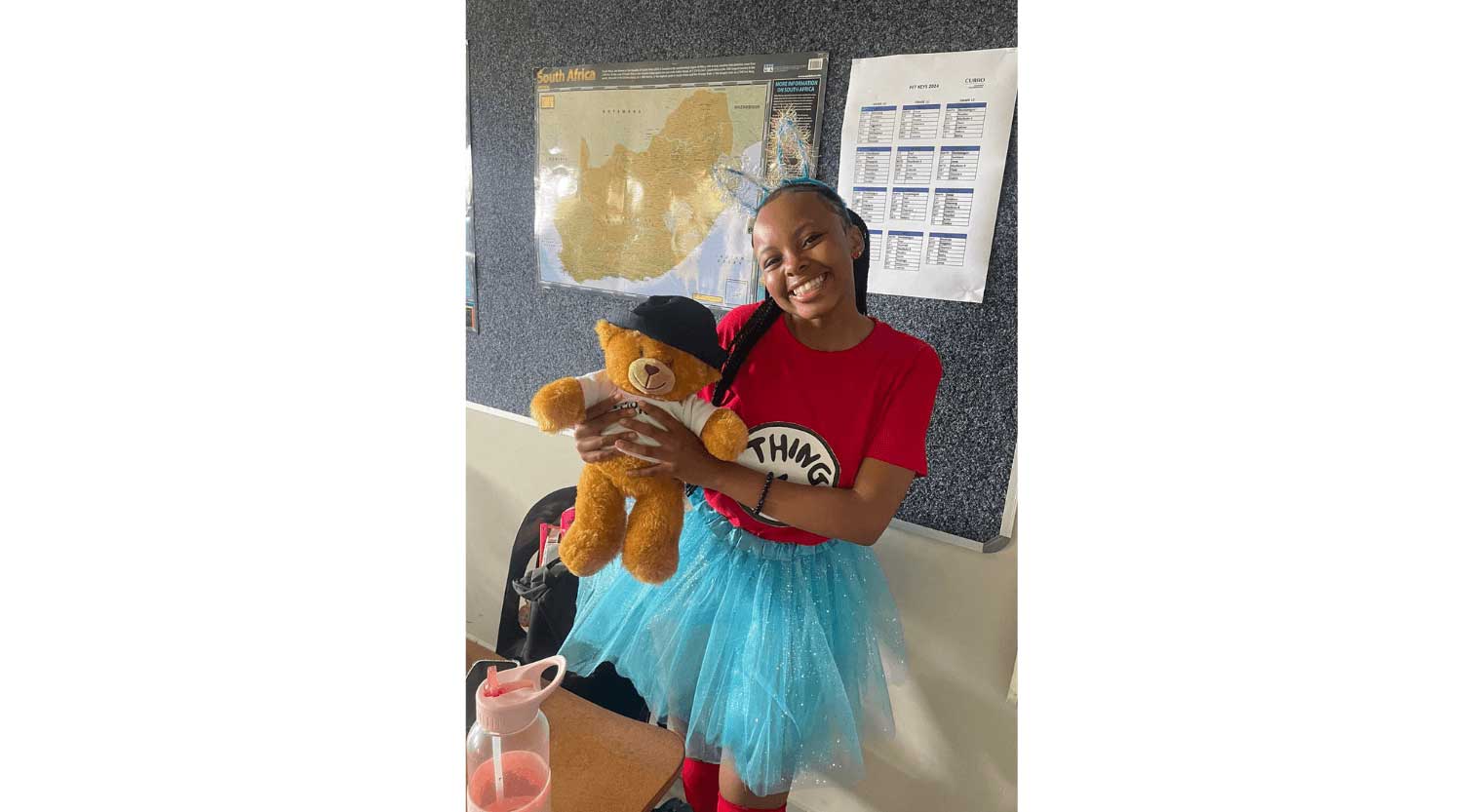 Girl dressed up as Dr Seuss character holding a stuffed teddy bear